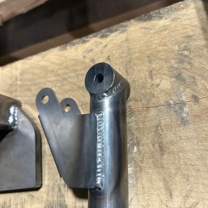 Close-up of a welded metal bracket on a wooden surface, showcasing welding details and craftsmanship.