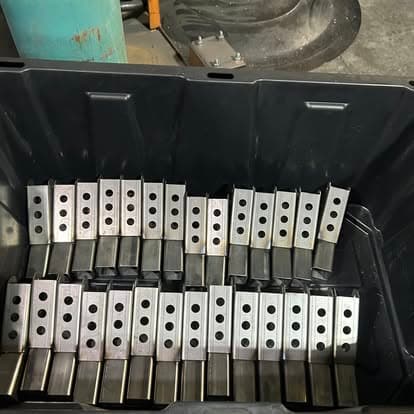 Metal brackets with holes arranged in a black storage container.