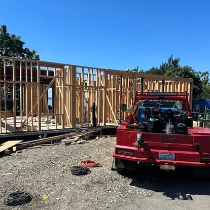 Construction site with wooden framing for a house and a red truck in the foreground.