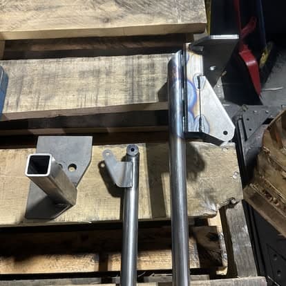 Metalworking tools on wooden pallets, featuring square and round steel tubing fittings.
